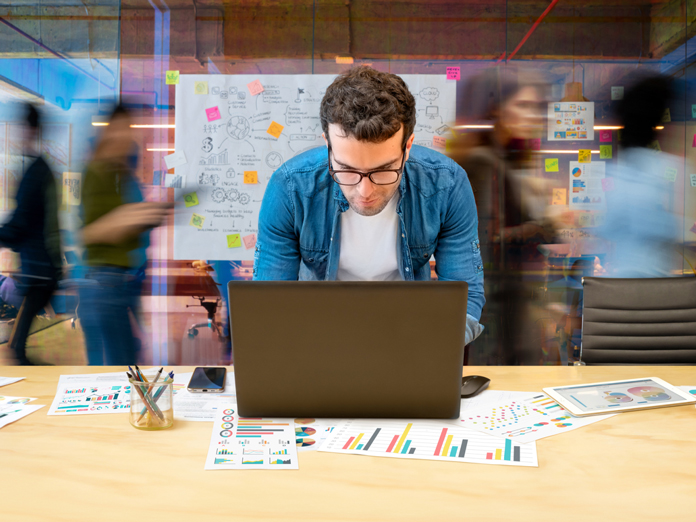 Man on computer with whiteboard in blurry background