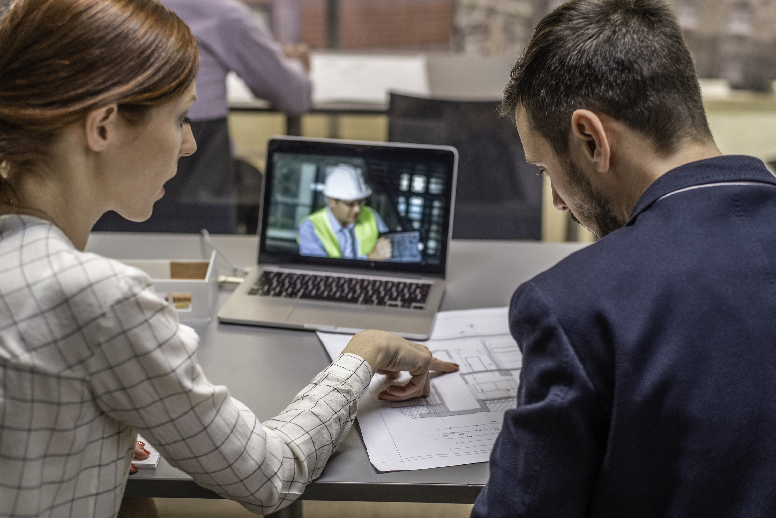 a man and a woman in front of a laptop showing a construction worker